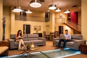 two people sitting on couches in a living room at Urban Green Hotel & Suites in San José