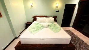 a bedroom with a bed with a bow tie on it at Abbi Holiday - Jaffna Hotel in Jaffna +6 photos