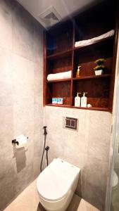 a bathroom with a white toilet and a shelf at Abbi Holiday - Jaffna Hotel in Jaffna