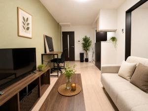 a living room with a couch and a tv at Rent菊水 -FIX HOME- in Sapporo