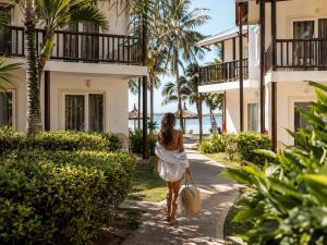 a woman in a white dress walking down a sidewalk at Lankraz Hotel Mauritius in Port Louis