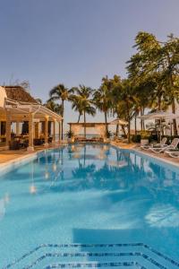 a large swimming pool with palm trees and umbrellas at Lankraz Hotel Mauritius in Port Louis