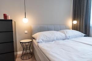 a bedroom with a bed with white sheets and a table at MCK Apartments in Košice