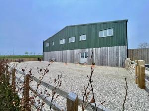 a green building with a fence in front of it at The Hayloft in Calne