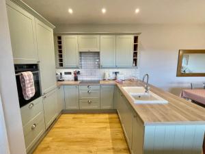 a kitchen with white cabinets and a sink at The Hayloft in Calne +3 photos