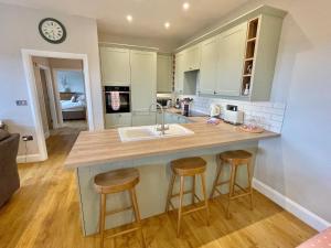 a kitchen with a sink and two bar stools at The Hayloft in Calne