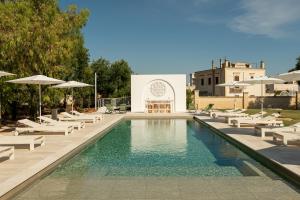a pool with chairs and umbrellas next to a building at Borgo Tufaia in Fasano
