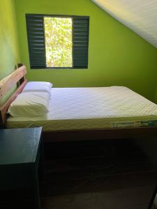 a bed in a green bedroom with a window at Refúgio Mundo dos Pássaros in Sao Jorge