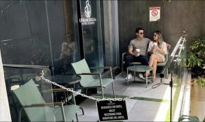 a man and a woman sitting in chairs outside a building at Urban Green Hotel & Suites in San José