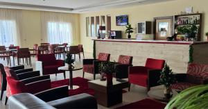 a waiting room with red chairs and a bar at Palace Hotel & SPA Termas do Bicanho in Soure