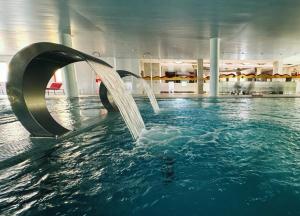 a swimming pool with a water fountain in a building at Palace Hotel Astúrias & Spa in Carvalhal