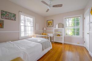 a white bedroom with a bed and two windows at Charming Waterfront Home with Mt Rainier View in Olympia