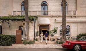 two people walking down a sidewalk in front of a building at Aminess Younique Korcula Heritage Hotel in Korčula