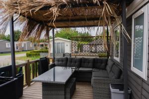 a patio with a couch and a table on a porch at Moderne chalet op het strand in Kropswolde
