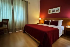 a hotel room with a large bed and a chair at Hotel Monte Rio Aguieira in Almaça +18 photos
