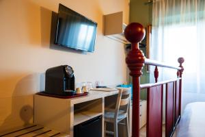 a room with a desk with a microwave and a television at Casale Verdeluna Wine Resort in Piglio