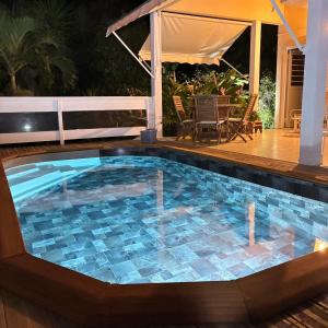 a swimming pool with a tile floor and a deck at La Siguine in Gourbeyre