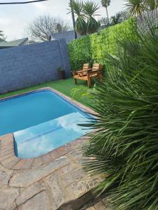 a swimming pool with a wooden bench next to a fence at Van Dyk guest house in Boksburg