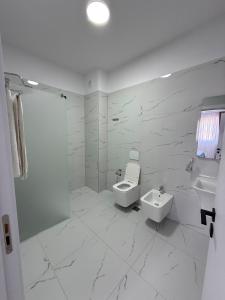 a white bathroom with a toilet and a sink at Best House Albania in Kamëz +30 photos