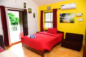 a bedroom with a red bed and a chair at Jes Guest House in Majorda