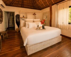 a bedroom with a large white bed with flowers on it at Olivia Oceanfront Tulum in Tulum