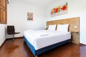 a bedroom with a large white bed and a chair at Quinta de Carvalhal - Casa da Vinha in Guimarães +30 photos