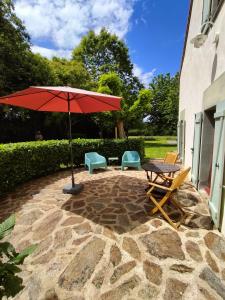 a patio with a table and chairs and an umbrella at Domaine Pouzoult, gîte l'Escalier in Sazeray +10 photos