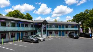 ein Gebäude mit auf einem Parkplatz abgestellten Autos in der Unterkunft Hotel OPUS Bronx Near Bay Plaza Mall in Bronx
