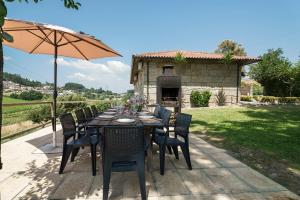 a table with chairs and an umbrella on a patio at Quinta de Carvalhal - Casa da Vinha in Guimarães