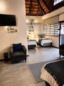 a bedroom with two beds and a chair and a tv at Forget me not Selfcatering Apartments in Nelspruit