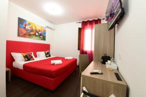 a hotel room with a red bed and a desk at 100 Passi dal Porto in Civitavecchia