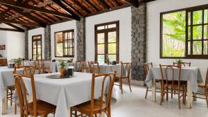 a dining room with white tables and chairs and windows at Vila Francesa Hotel in Penedo