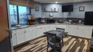 a kitchen with white cabinets and a table in it at Baymont by Wyndham Fort Collins in Fort Collins