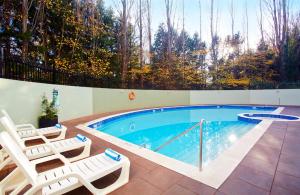 a swimming pool with two lounge chairs next to it at Crowne Plaza Canberra by IHG in Canberra