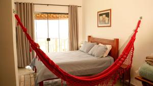 a red hammock bed in a bedroom with a window at Chales Paraíso STL in São Thomé das Letras