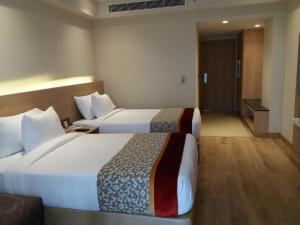 a hotel room with two beds and a bathroom at Oaks Bodhgaya in Bodh Gaya