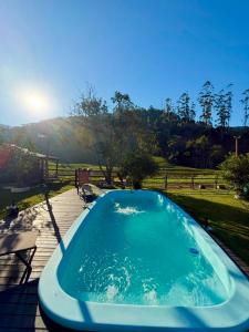 a hot tub on a deck next to a field at Sitio encantos do vale Casa in Major