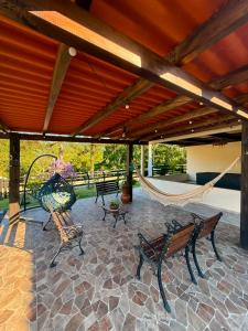 a patio with benches and a hammock under a roof at Sitio encantos do vale Casa in Major