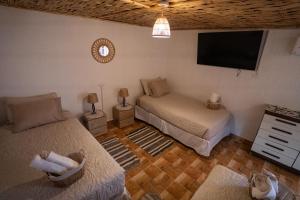 a bedroom with two beds and a flat screen tv at Karrizo lodge in San Pedro de Atacama