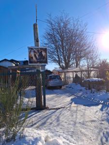 a sign in the snow with a car parked at Alojamiento Adonai in Tolhuin