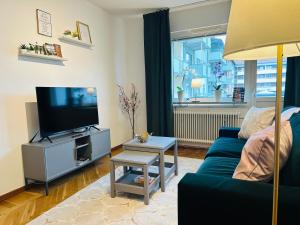 a living room with a blue couch and a tv at Prinshöjden Apartments - Katrineholm Central in Katrineholm