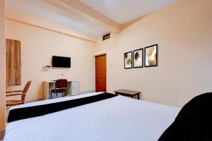 a bedroom with a bed and a desk and a television at Hotel O Snow White in Bhadrak +23 photos