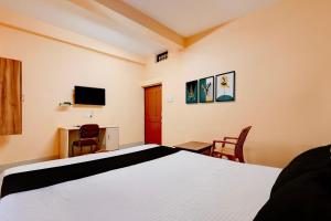 a bedroom with a bed and a desk and a television at Hotel O Snow White in Bhadrak