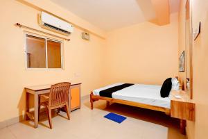 a bedroom with a bed and a desk and a window at Hotel O Snow White in Bhadrak