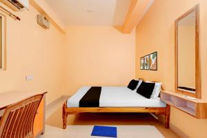 a bedroom with a bed and a mirror at Hotel O Snow White in Bhadrak