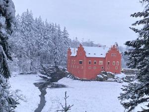 a large red building in a snow covered forest at Chalupa Na konci Lhoty in Pluhův Žďár +8 photos