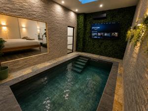 a swimming pool in a room with a bed and a television at Eaux Spa Rive Droite in Rouen