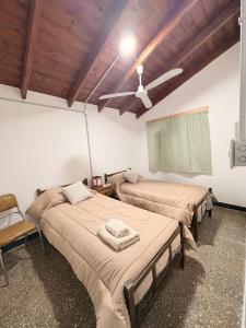 a bedroom with two beds and a ceiling fan at Villa Valeria in General Acha +3 photos