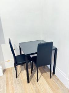 a black dining room table with two black chairs at Logement Angèle in Malesherbes