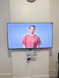 a flat screen tv on a wall with a man on it at Logement Angèle in Malesherbes